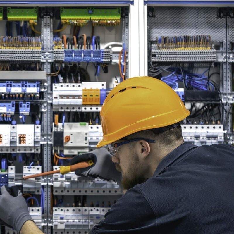 Electrician working in switchboard with electrical connection cable, copy space. Male electrician working in switchboard with electrical connection cable, connecting equipment with tools, complex work concept. Web, social media banner template. Copy space.